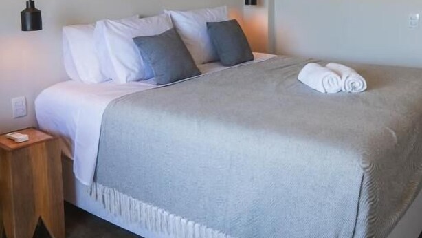 A bedroom with a bed, bedside tables, wall-mounted artwork, and an air conditioning unit. - Kali House (Tibau do Sul)