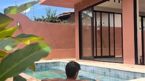 A person relaxing in a swimming pool with a modern house in the background. - Kali House (Tibau do Sul)
