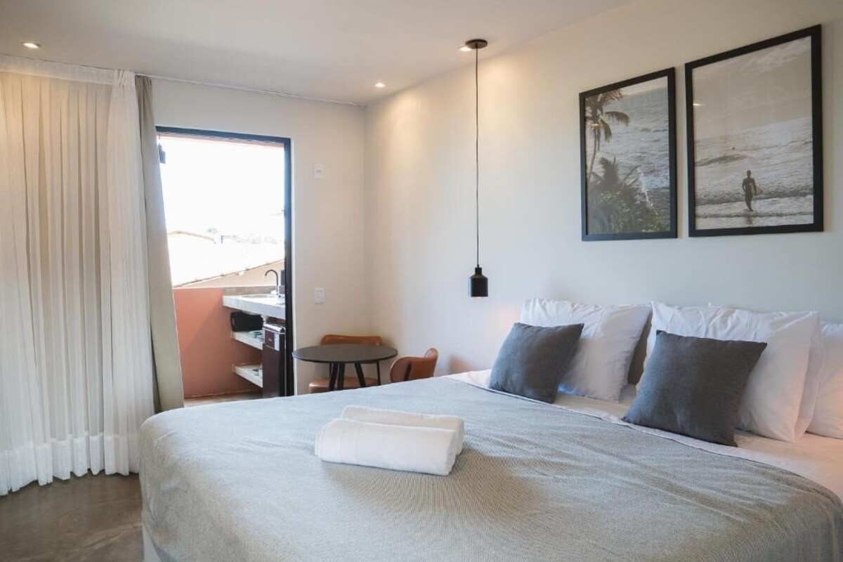 A hotel room with a bed, a desk, a chair, and two framed pictures on the wall.