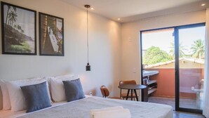 A hotel room with a bed, a desk, a chair, and a sliding glass door leading to a balcony. - Kali House (Tibau do Sul)