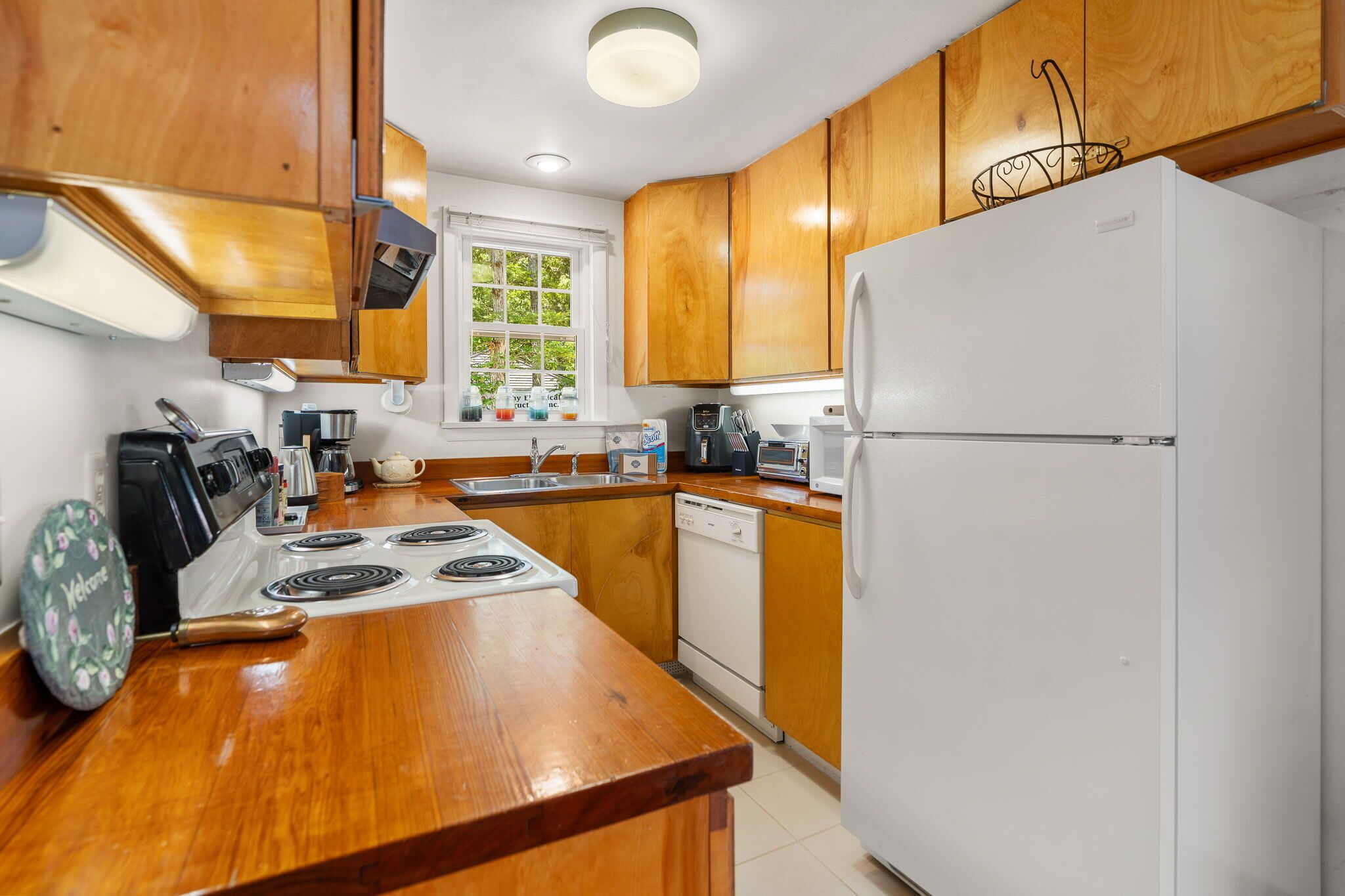 A kitchen with wooden cabinets, a white refrigerator, a stove, and a dishwasher.