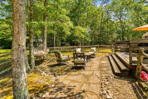 Eine Holzterrasse mit Gartenmöbeln, umgeben von Bäumen und einem eingezäunten Bereich.