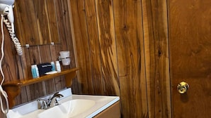 Een houten badkamer met een wastafel, spiegel en toiletartikelen.