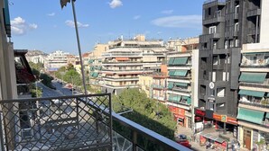 En balkon med udsigt over bybilledet, med bygninger og en vej.