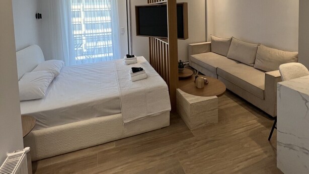 Et moderne hotelværelse med seng, sofa, fjernsyn og et vindue med gardiner.