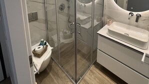 Et moderne badeværelse med en glasafskærmet brusekabine, et spejl og en vaskebord.