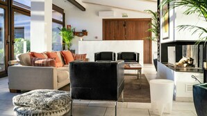 Ein modernes Wohnzimmer mit einer Couch, Sesseln, einem Couchtisch und einem Kamin.