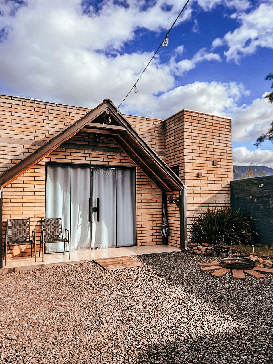 A modern building with a brick facade, a large sliding door, and a gravel driveway.