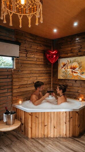A wooden room with a hot tub, a heart-shaped balloon, and a painting on the wall. - Chalés Manacá dos Canyons (Praia Grande)