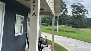 A house with a porch, a number 27A, and a view of a grassy field.