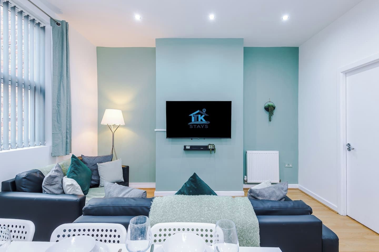 Ein modernes Wohnzimmer mit einer Sofagarnitur, einem Flachbildfernseher und einem Essbereich mit Stühlen und einem Tisch.