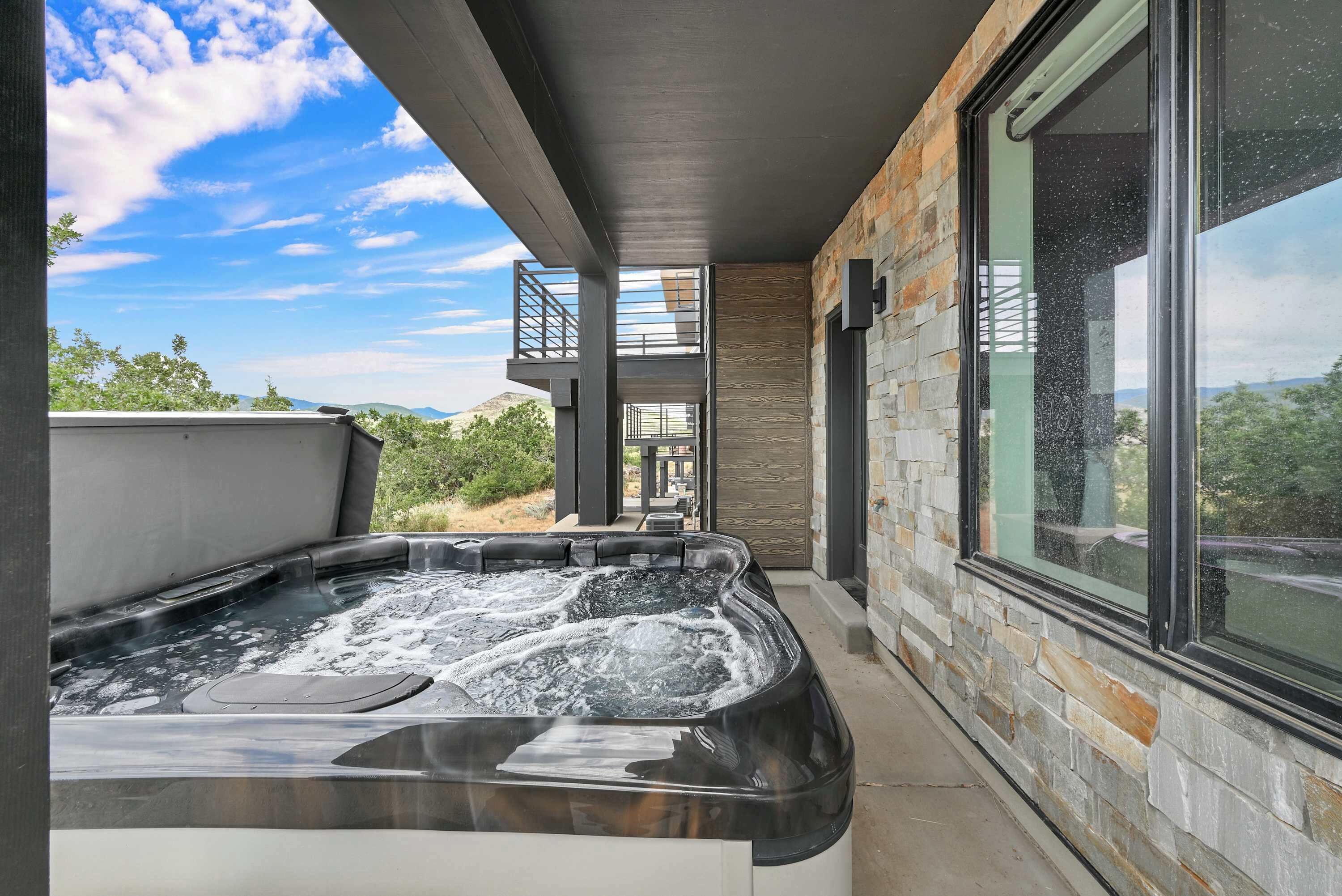 A hot tub with a view of the outdoors, a stone wall, and a window.