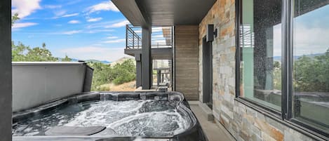 Een hottub met uitzicht op de natuur, een stenen muur en een raam.