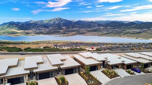 A residential area with modern houses, a road, and a lake with mountains in the background. - 3BR Park City View Home | Hot Tub | Pet-Friendly (Hideout)