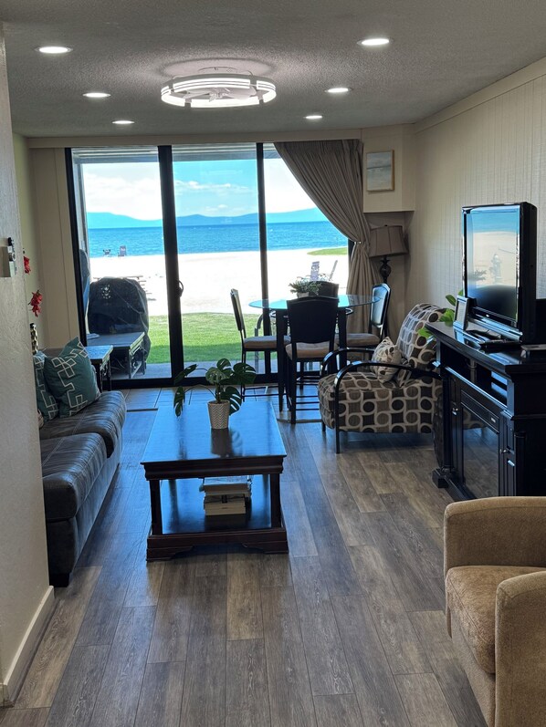 Una sala de estar con sofá, mesa de centro, televisor y vista al mar.