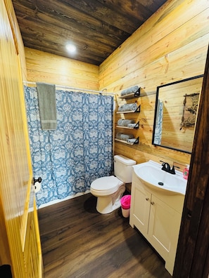 Een betegelde badkamer met toilet, wastafel en douchehoek.
