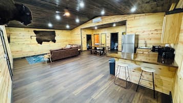 A log cabin interior with a living area, kitchen, and a large buffalo mounted on the wall.