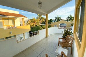 A covered outdoor area with a tiled floor, a railing, and a view of a building with a tiled roof. - Hotel y Condominios Jaroje (Crucecita)