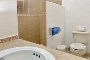 Un baño con bañera, inodoro y zona de ducha.