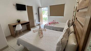 A hotel room with two beds, a desk, a chair, a TV, and a window.