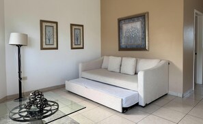 Una sala de estar con un sofá, una lámpara y tres cuadros en la pared.