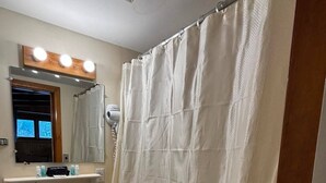 Un bagno con tenda doccia, lavandino, specchio e finestra vista.