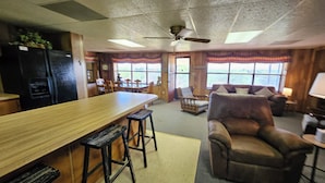 A kitchen with a bar, wooden stools, a refrigerator, and a dining table. - Private Lakefront Retreat - Fishing, Game Room - Lake Colorado City TX (Colorado City)