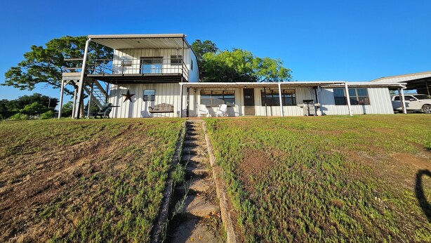 A two-story house with a balcony, a covered porch, and a small attached garage. - Private Lakefront Retreat - Fishing, Game Room - Lake Colorado City TX (Colorado City)
