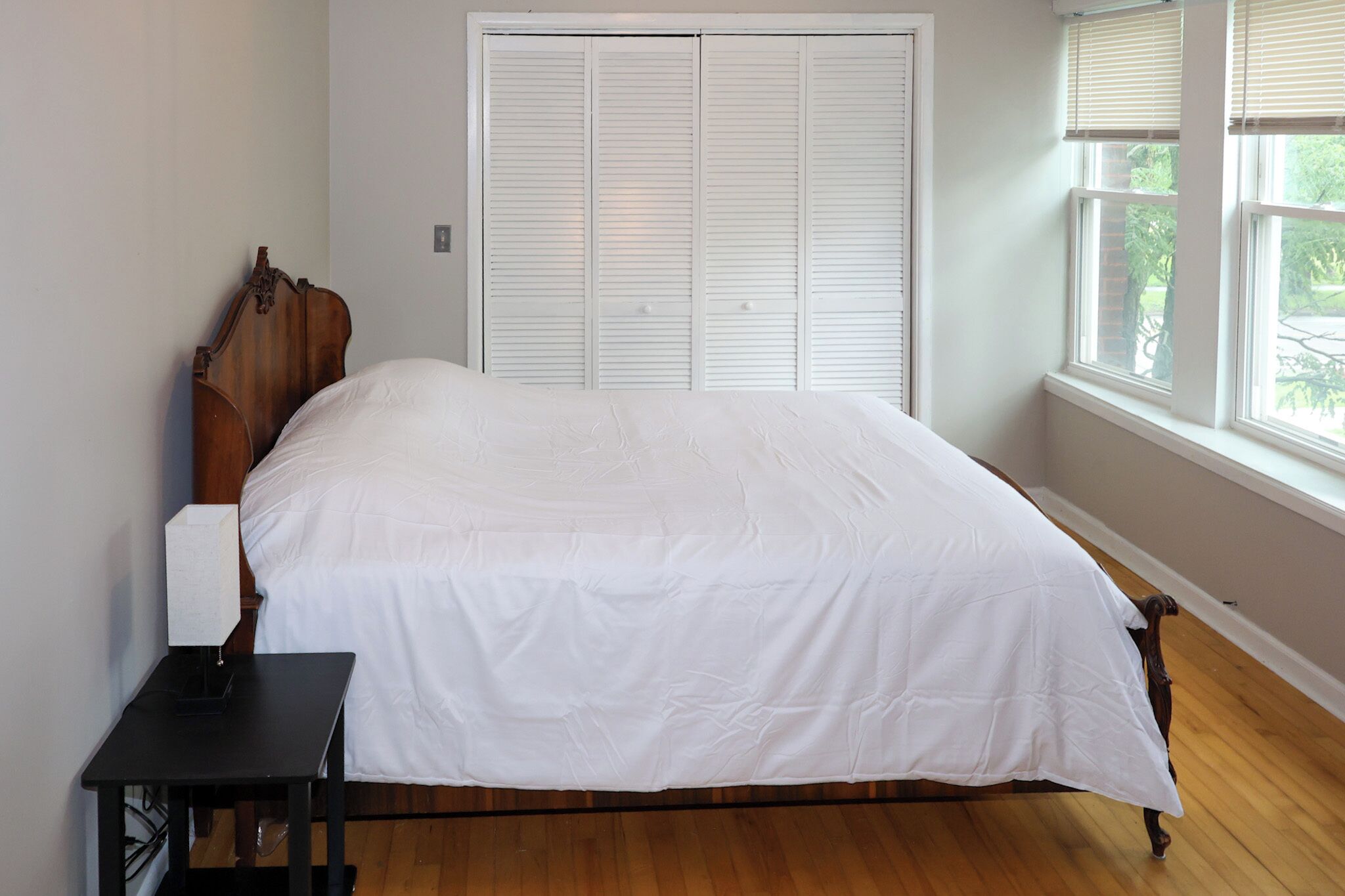 Une chambre à coucher avec un lit en bois, une table de chevet et une armoire blanche.