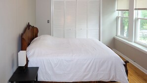 A bedroom with a wooden bed, a nightstand, and a white closet. - Spacious 5-bedroom house in Chicago with AC Near Obama Center & UChicago (Chicago)