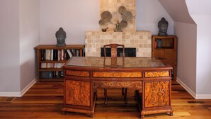 A traditional wooden desk with intricate carvings, a fireplace with decorative plates, and bookshelves filled with books. - Spacious 5-bedroom house in Chicago with AC Near Obama Center & UChicago (Chicago)