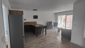 A modern kitchen with a wooden dining table, a refrigerator, and a TV. - Premium Luxury Apartment (Dunkerque)