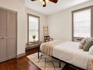Een slaapkamer met een bed, bureau, stoel en kledingkast.