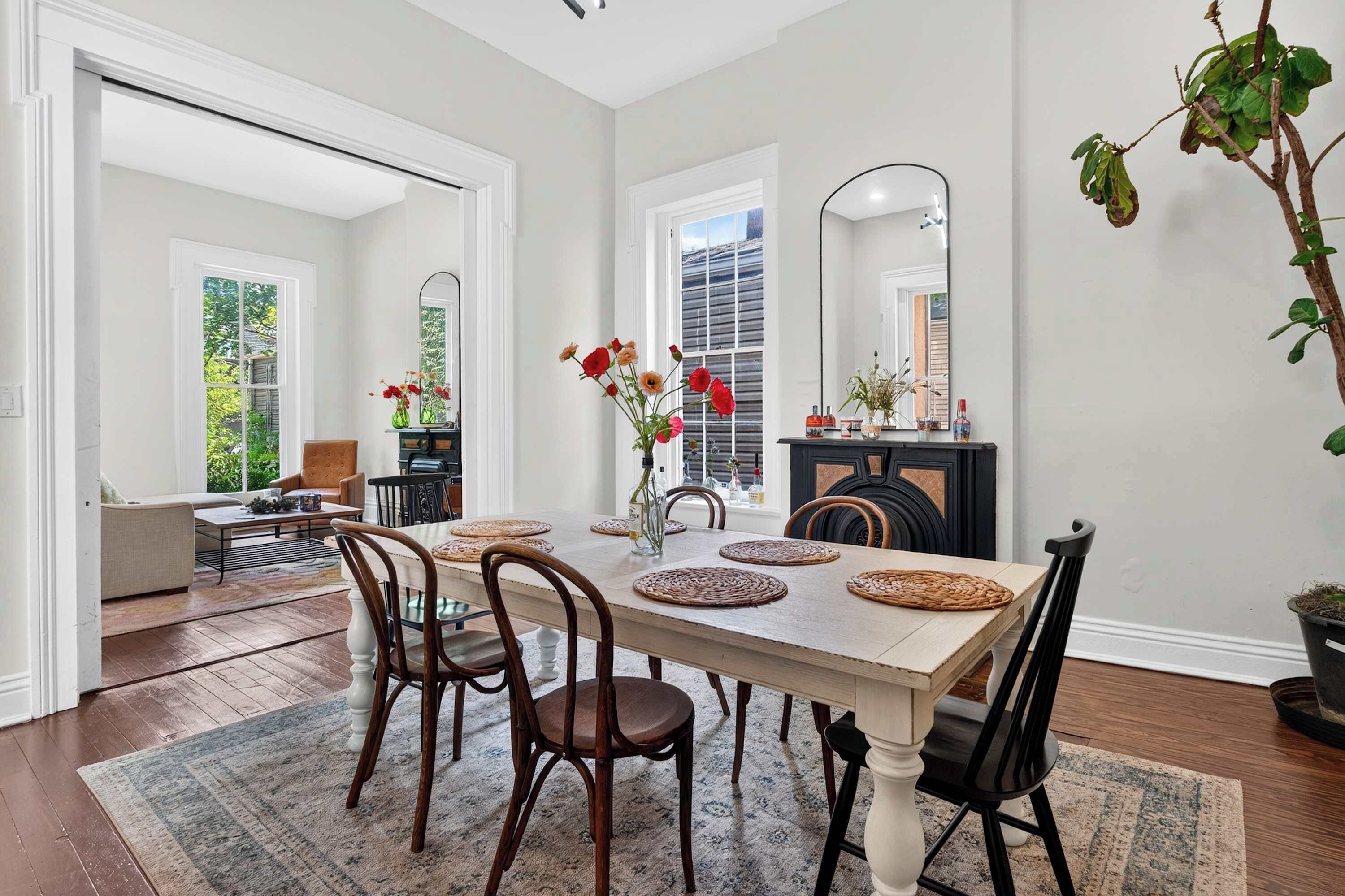 A dining room with a wooden table, chairs, and a large mirror.
