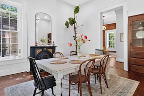 A dining area with a white table, wooden chairs, and a vase with flowers. - Relaxing home w/ poker lounge & spacious backyard! (Louisville)