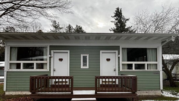 Une petite cabane comprenant deux pièces, avec un porche à l’avant et des marches menant à l’entrée.