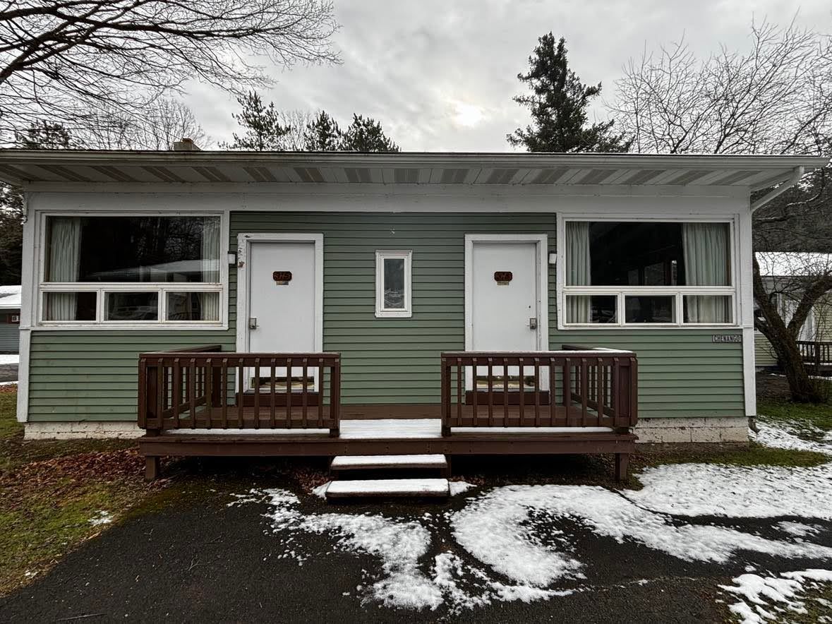 A small, two-room cabin with a front porch and steps leading to the entrance.