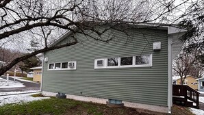 Une maison de plain-pied à l’extérieur vert, dotée d’un petit porche et d’une fenêtre bien visible.