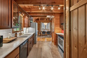 Ein Holzblockhaus-Interieur mit Küche, Essbereich und Blick ins Freie.