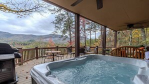 Una vasca idromassaggio su una terrazza con vista sulle montagne e sugli alberi.