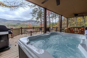 Ein Whirlpool auf einer Terrasse mit Blick auf Berge und Bäume.