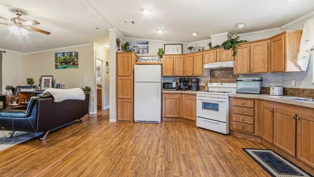 Una cocina moderna con armarios de madera, refrigerador, estufa, microondas y un comedor con sofá y mesa de centro.