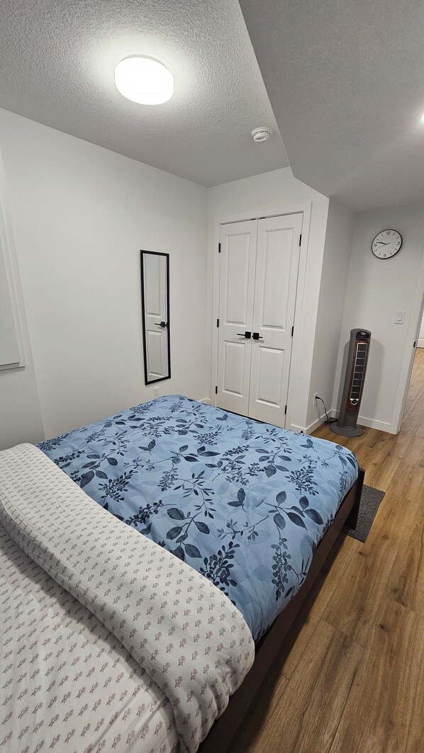 Una camera da letto con un letto, un armadio, uno specchio, una sveglia e un termosifone.