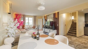 Un salon moderne avec un canapé, une table à manger et un escalier menant à une autre pièce.