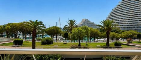 A modern urban park with palm trees, a water feature, and a large building in the background.