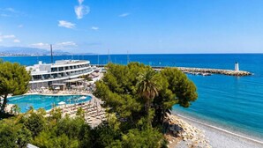Un resort con piscina, playa y un faro al fondo.