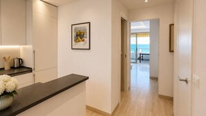 Un pasillo con mostrador de cocina, un cuadro enmarcado y vista a un balcón.