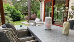 A patio with wicker furniture, a stone table, and a white vase.