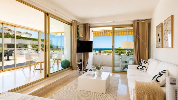 A modern living room with a sofa, coffee table, and a TV. - 3-Bedroom Apartment with Panoramic Ocean View · 100 m² Terrace · Marina (Villeneuve-Loubet)
