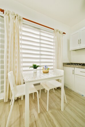 A modern kitchen with white cabinetry, a dining table with chairs, and a window with blinds. - Peaceful 1bedroom studio with AC in charming Cabrera (Cabrera)